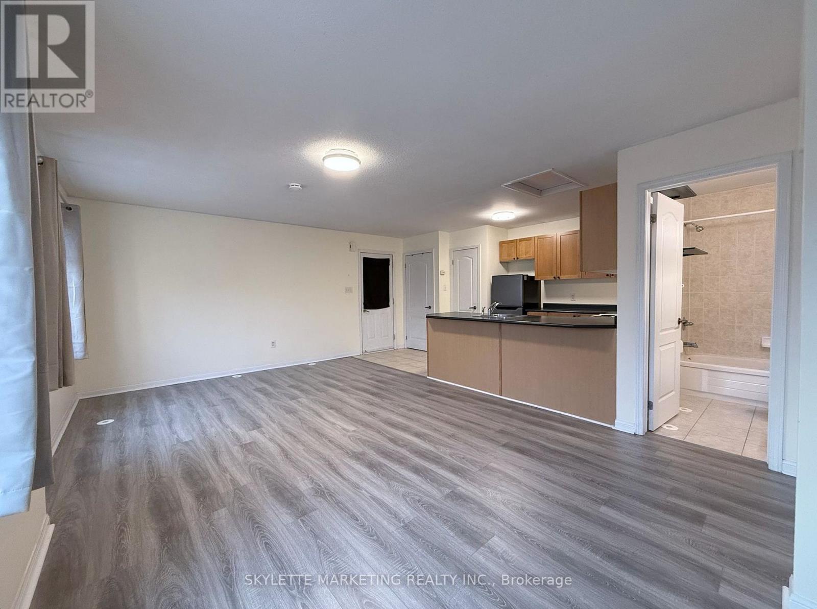 A spacious room with a kitchen area in the background.