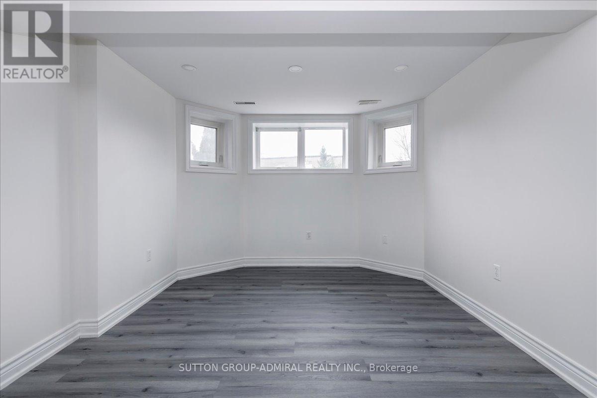 A spacious room with wooden flooring and white walls.