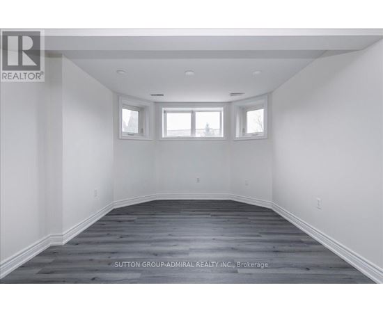 A spacious room with wooden flooring and white walls.