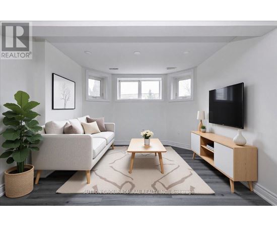 A living room with a white couch, a wooden coffee table, and a flat-screen TV mounted on the wall.