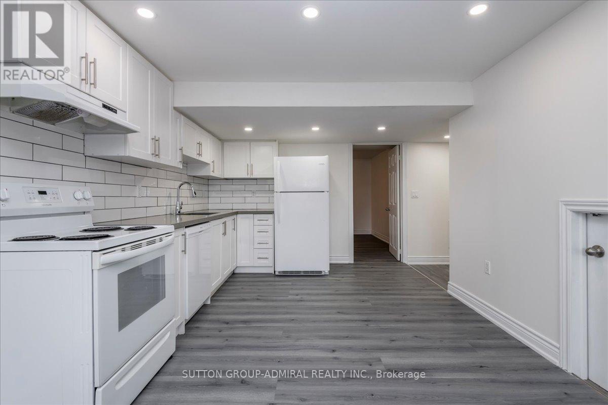 A white kitchen with a stove top oven and a refrigerator.