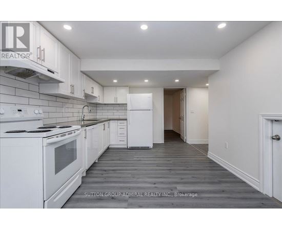 A white kitchen with a stove top oven and a refrigerator.