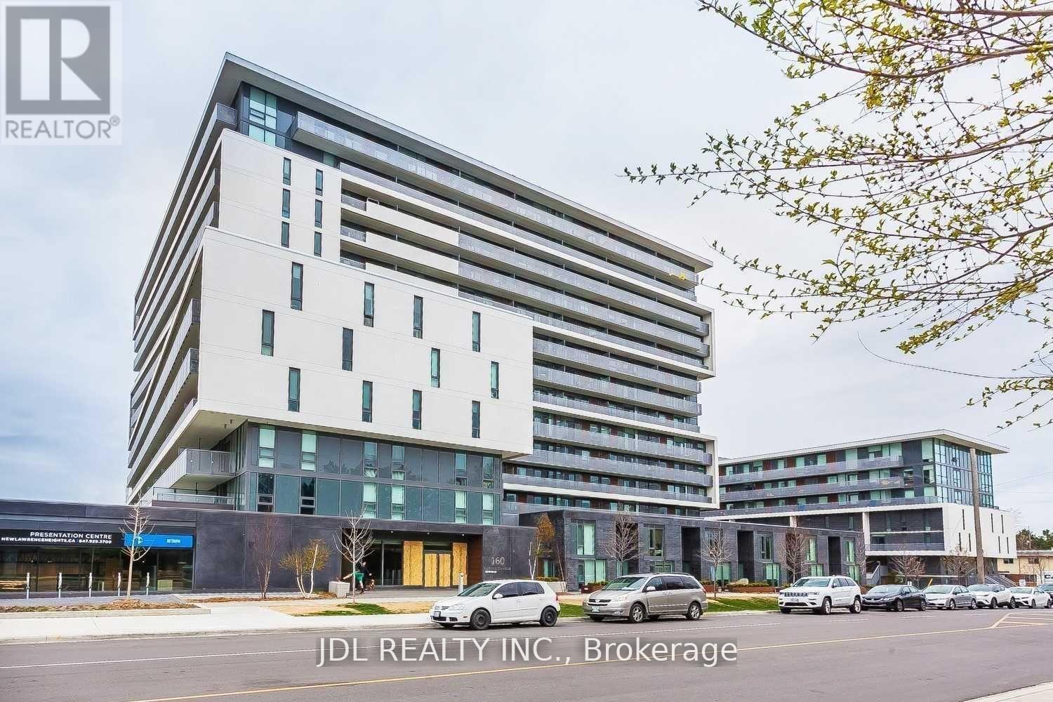 A modern multi-story building with a parking lot in front.
