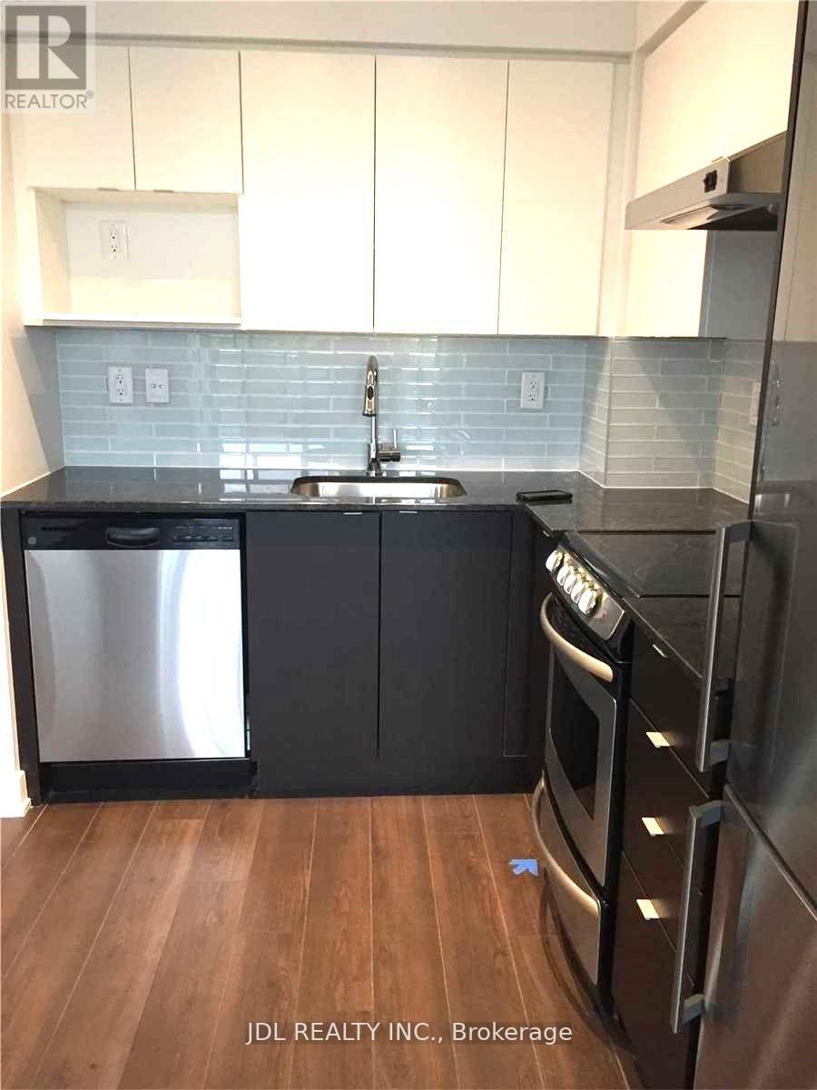 A kitchen with black appliances and wooden floors.
