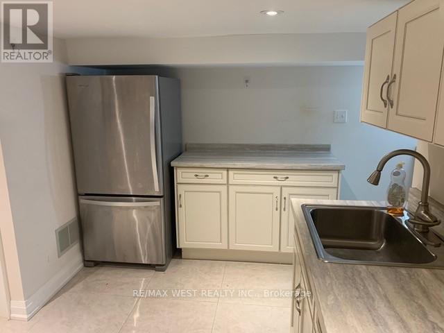 A kitchen with a stainless steel refrigerator, white cabinets, and a granite countertop.