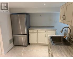 A kitchen with a stainless steel refrigerator, white cabinets, and a granite countertop.