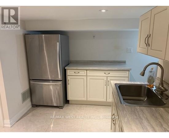 A kitchen with a stainless steel refrigerator, white cabinets, and a granite countertop.