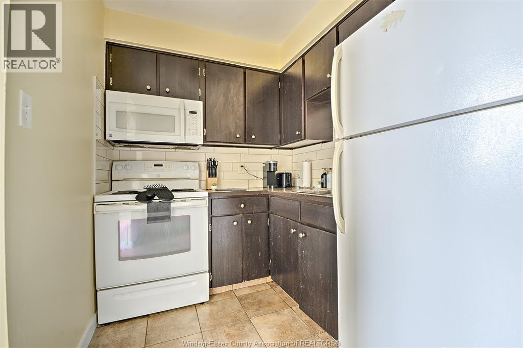 A kitchen with a white refrigerator, white oven, and black cabinets.