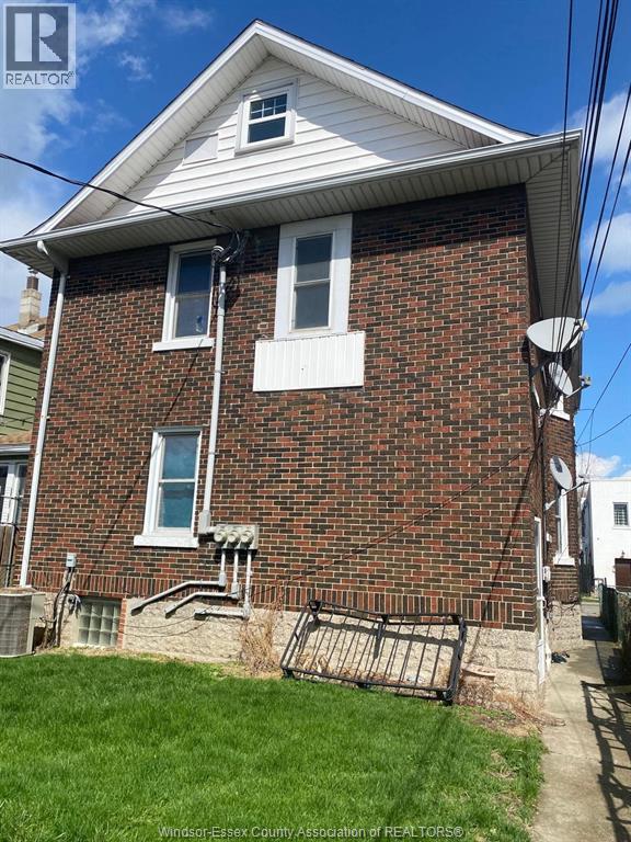 A brick house with a white window and a satellite dish on the roof.