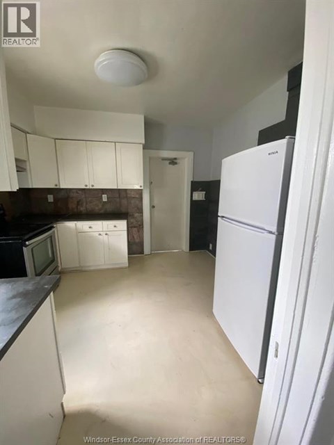 A kitchen with white cabinets and a white refrigerator.