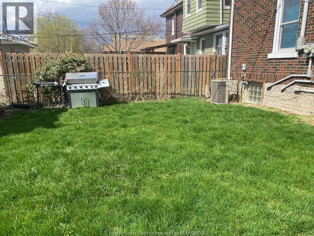 A backyard with a wooden fence and a green lawn.