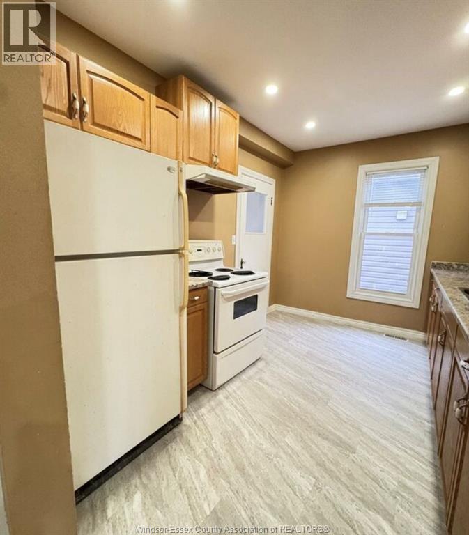 A kitchen with a white refrigerator, a white stove, and wooden cabinets.