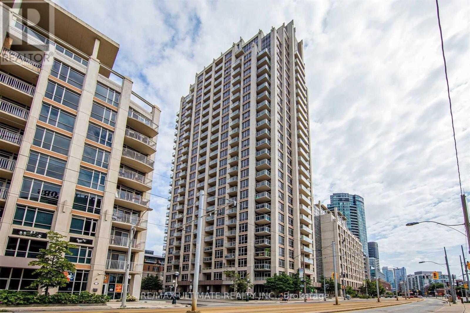 A tall building with many windows stands next to a shorter building with balconies.