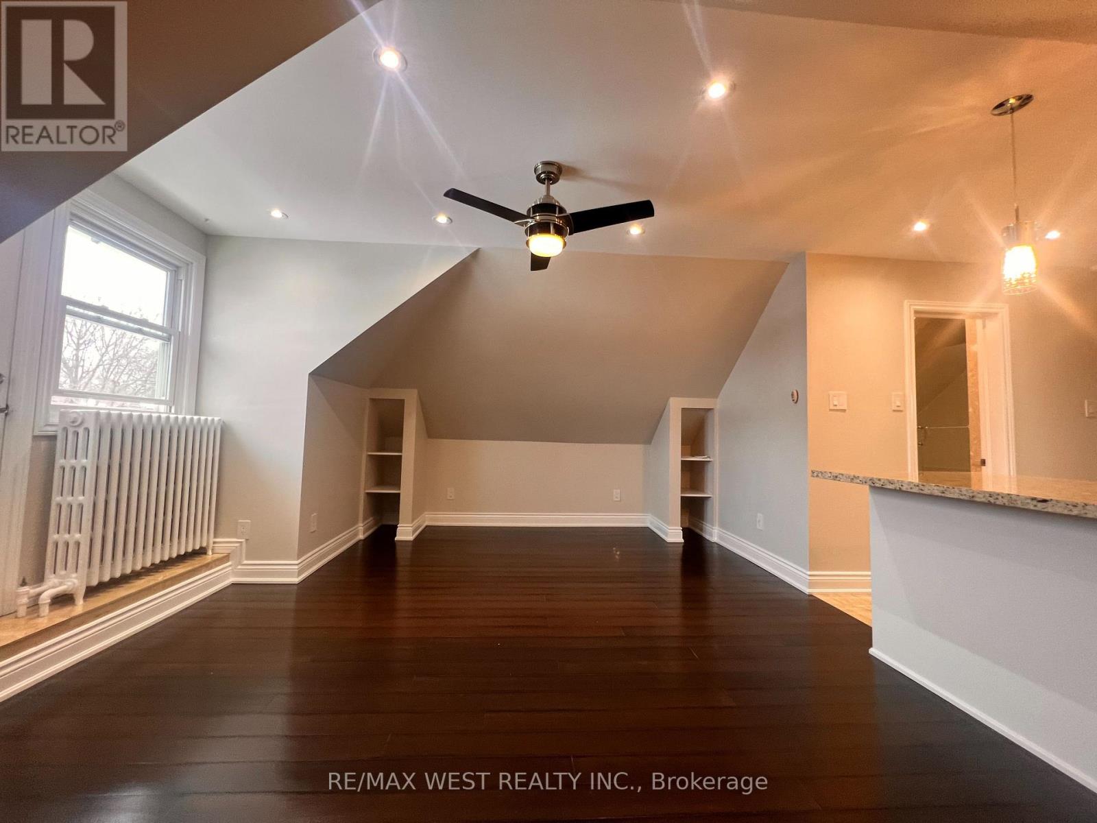 A spacious room with a ceiling fan and wooden flooring.