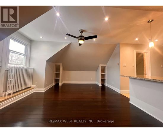 A spacious room with a ceiling fan and wooden flooring.