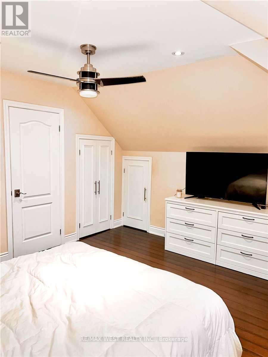 A bedroom with a bed, dresser, and ceiling fan.
