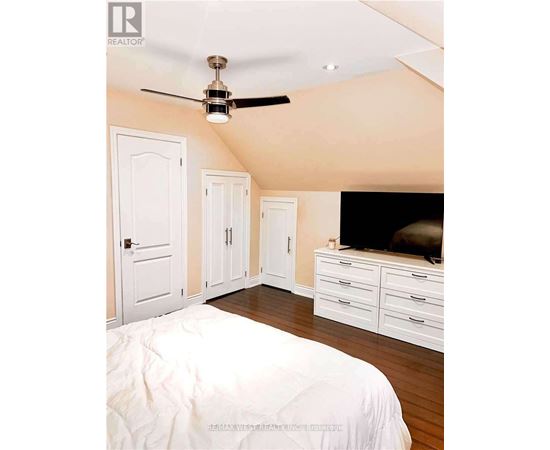 A bedroom with a bed, dresser, and ceiling fan.