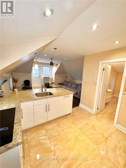 A kitchen with a sink and cabinets under a window.