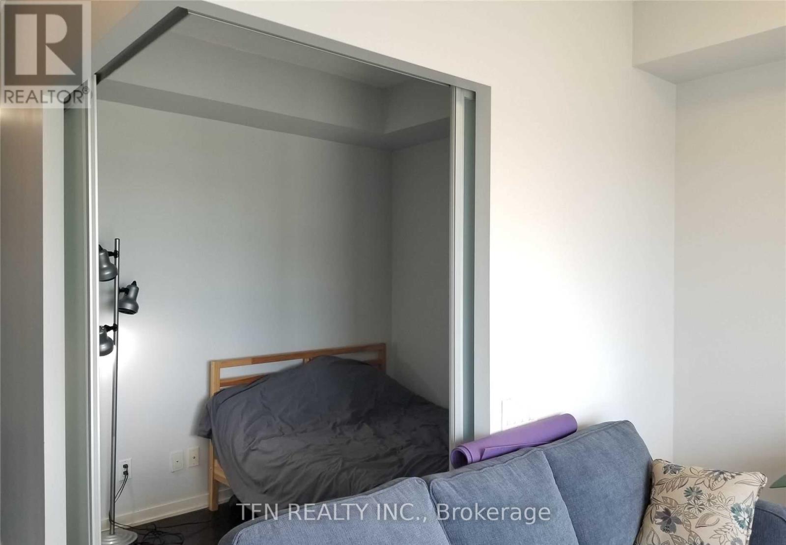 A bedroom with a bed and a couch in front of a glass door.