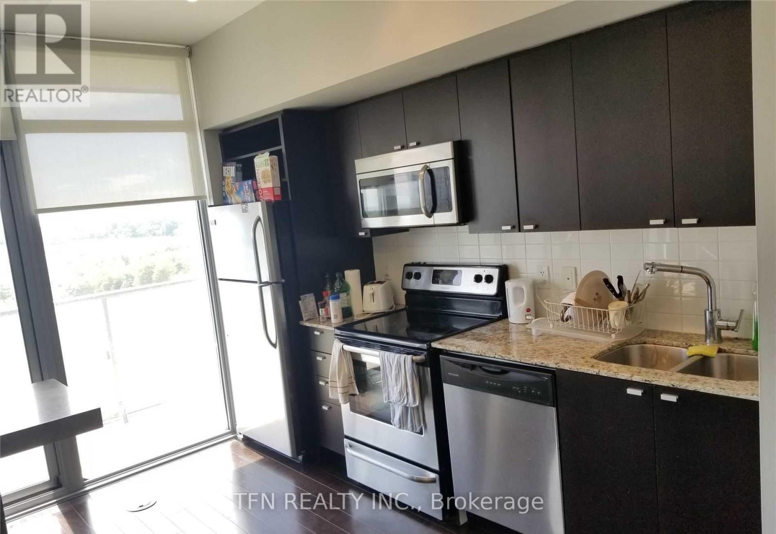 A modern kitchen with black cabinets and stainless steel appliances.