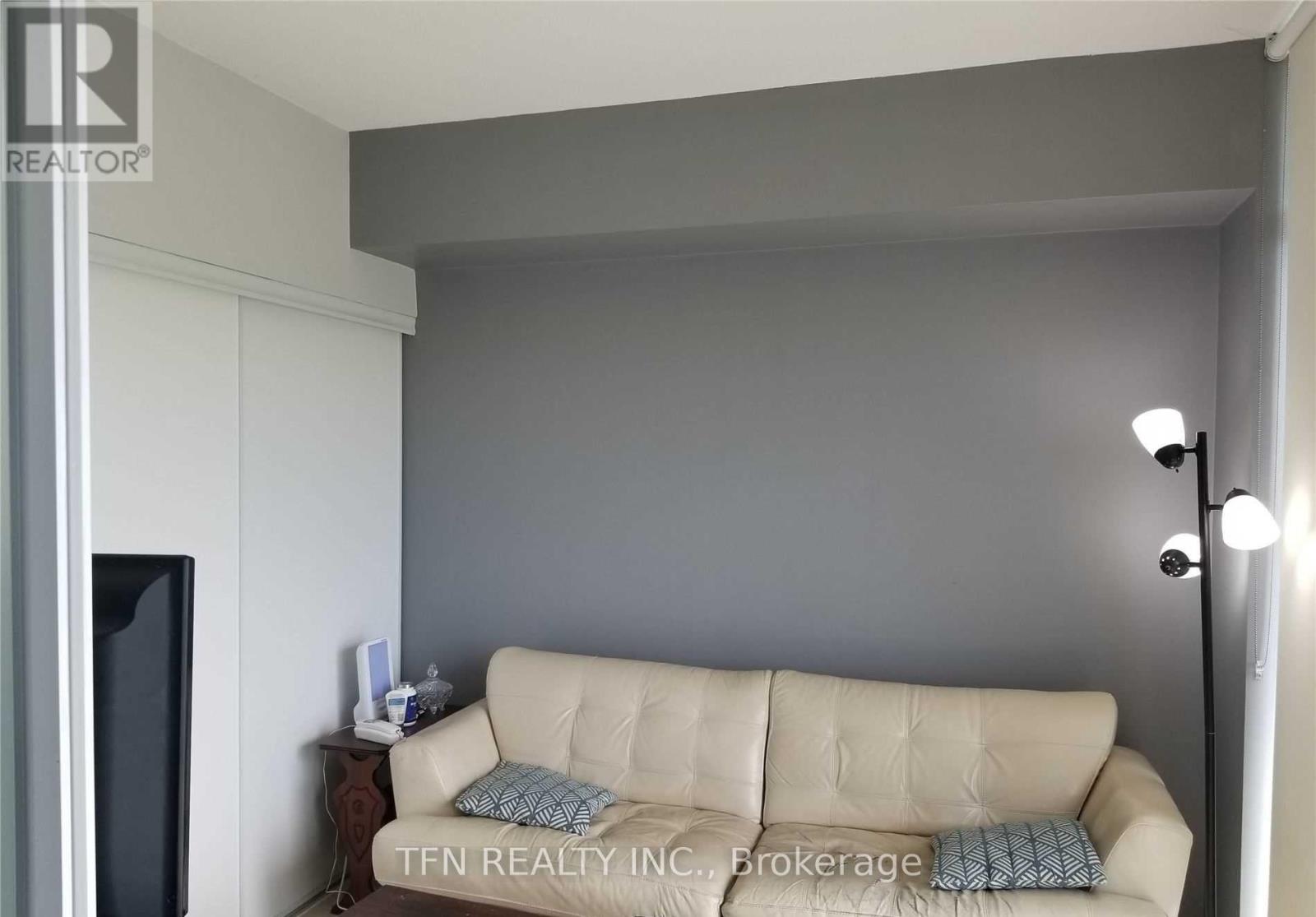 A living room with a beige couch and a television.