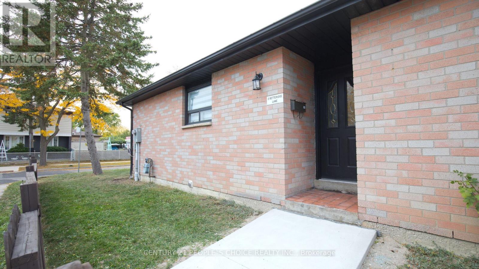 A brick house with a black door and a small porch.