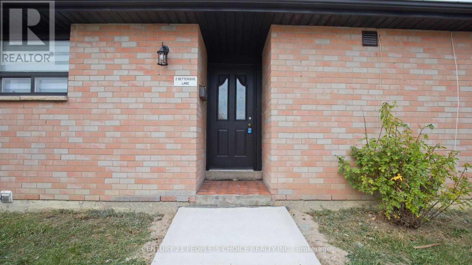 A brick building with a black door and a sign that says REALTOR.