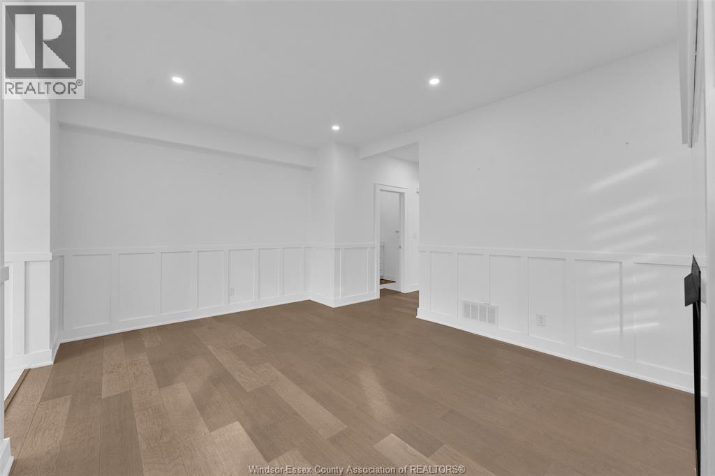 A spacious room with wooden flooring and white walls.