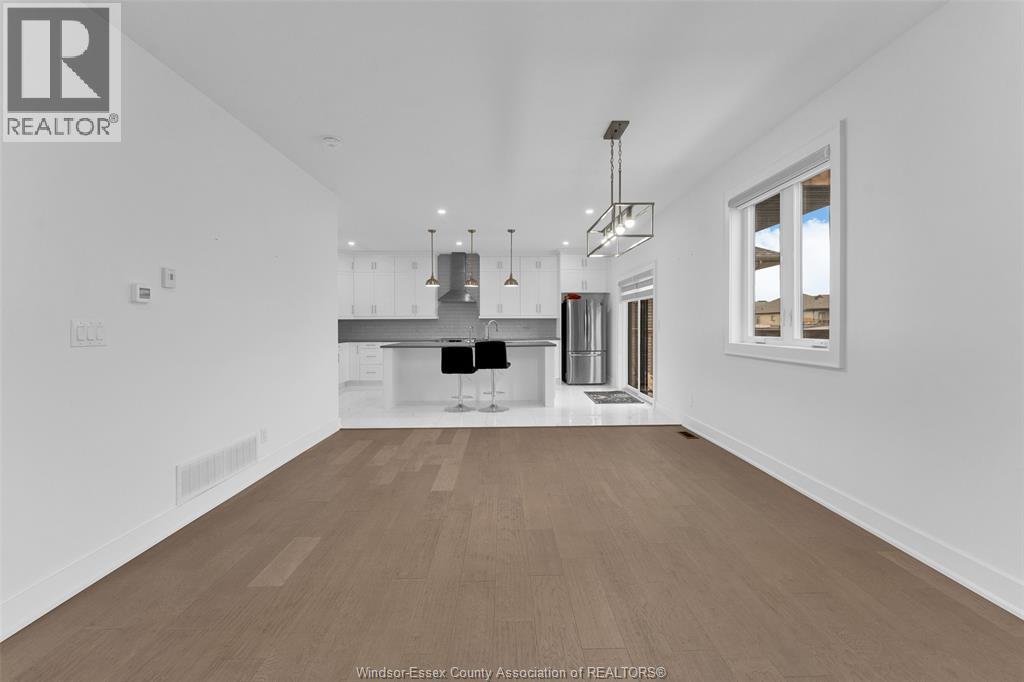 A spacious kitchen with white cabinets and a wooden floor.