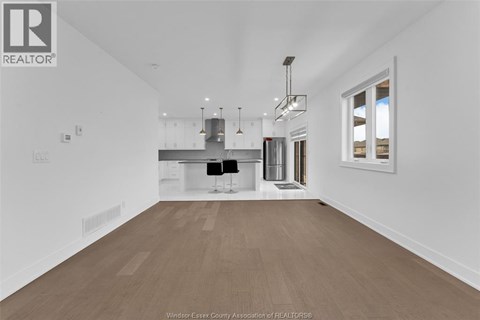 A spacious kitchen with white cabinets and a wooden floor.
