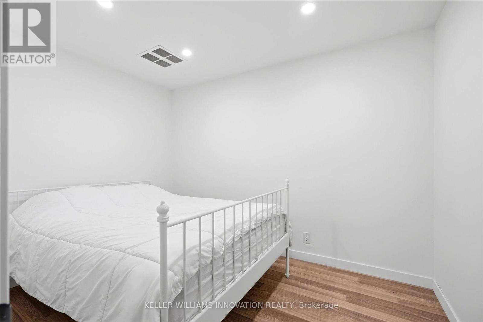 A white bed with a white mattress in a white bedroom.