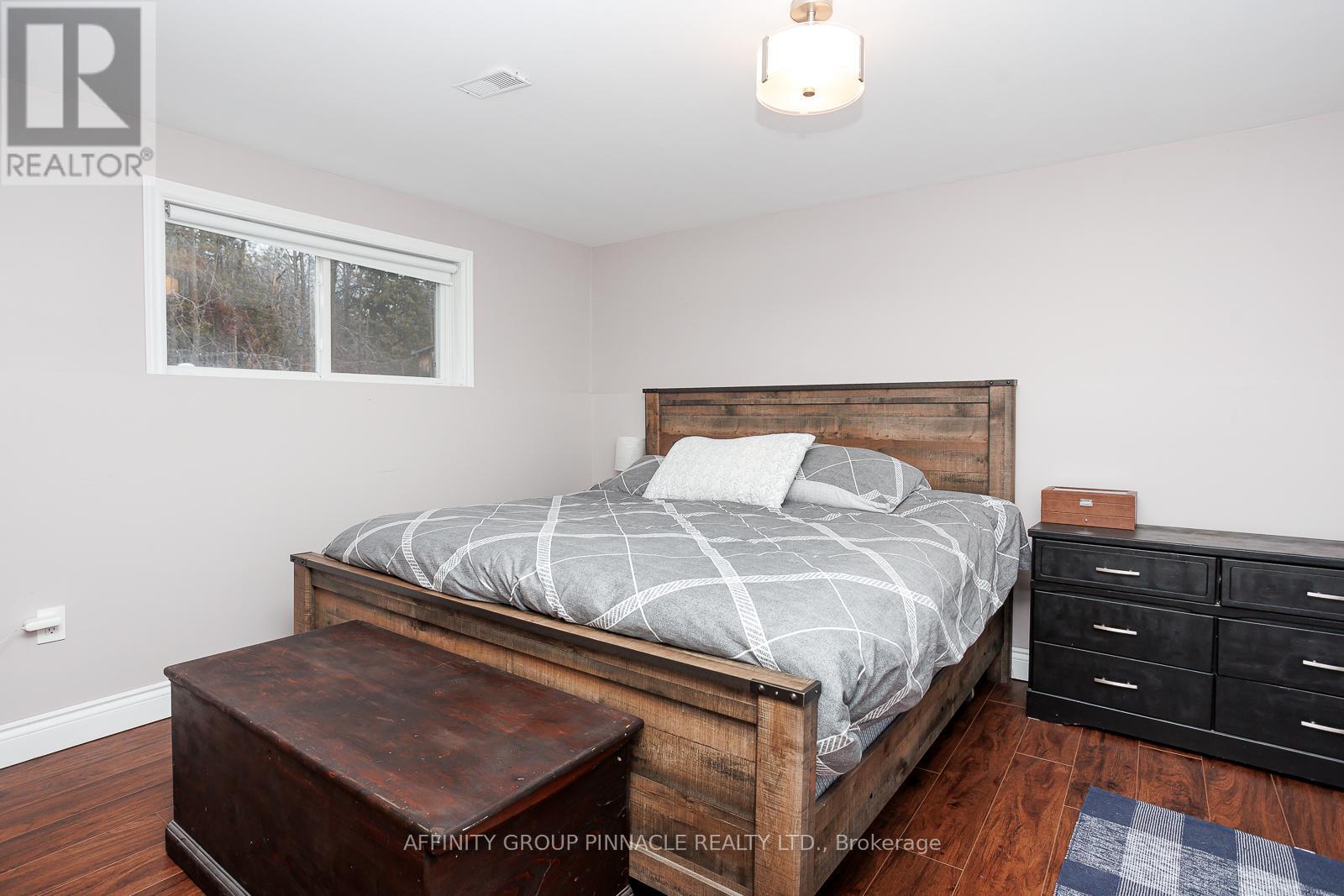 A bedroom with a bed, nightstand, and window.