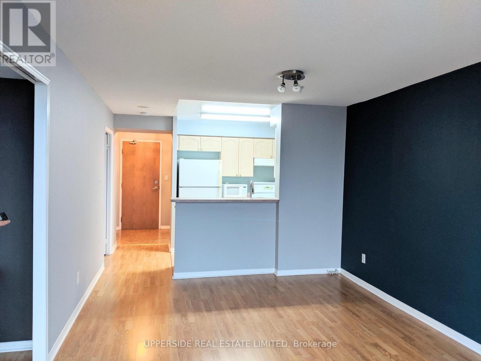 A room with a wooden floor and a door leading to another room.