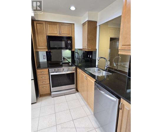 A kitchen with wooden cabinets and black countertops.