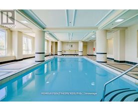 A large indoor swimming pool with a blue tinted water.