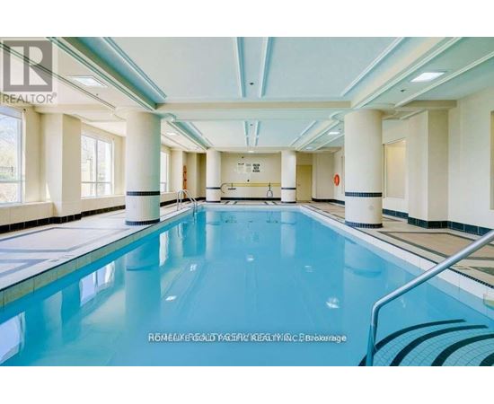 A large indoor swimming pool with a blue tinted water.