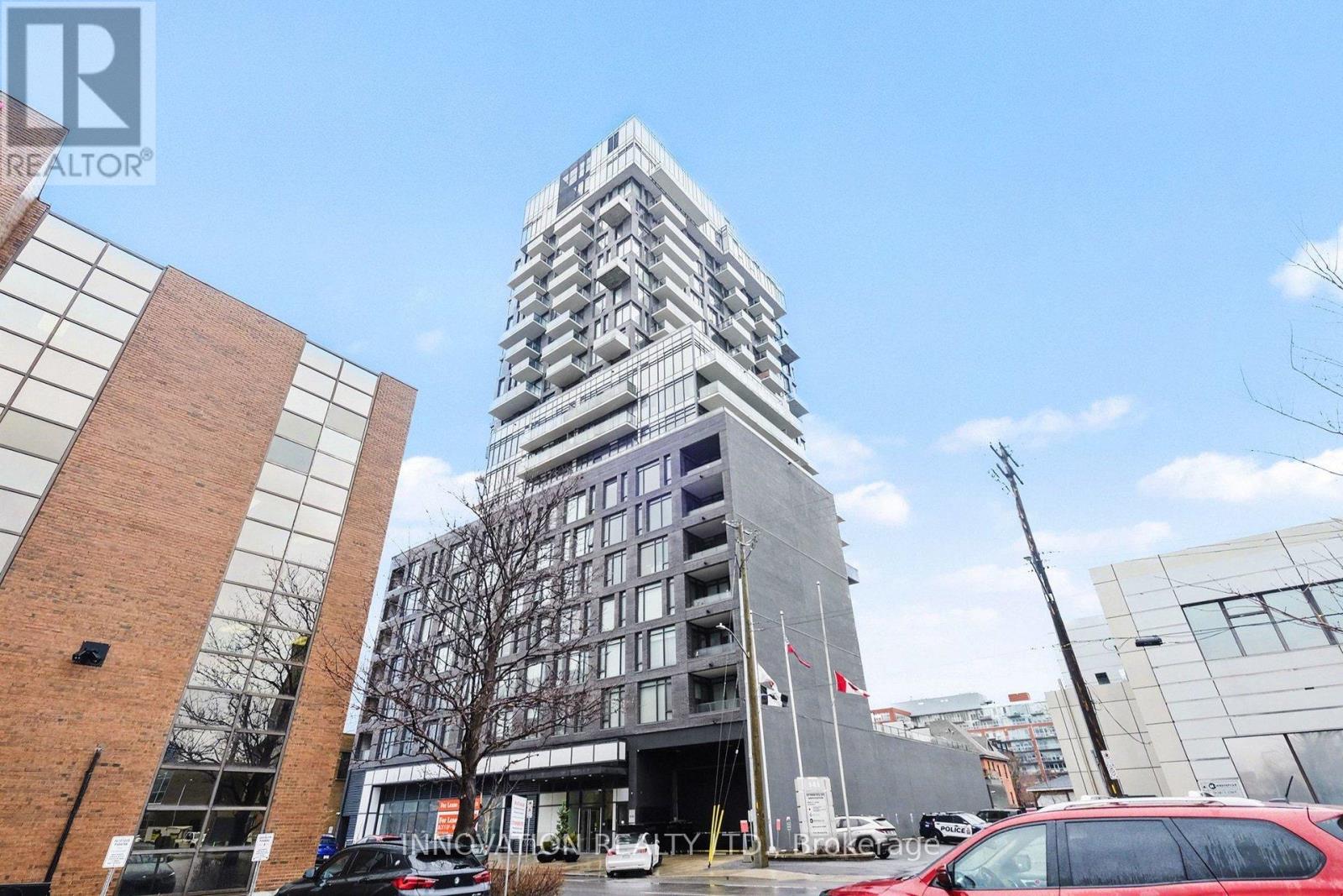 A tall building with a glass facade stands in front of a smaller brick building.