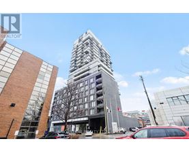 A tall building with a glass facade stands in front of a smaller brick building.