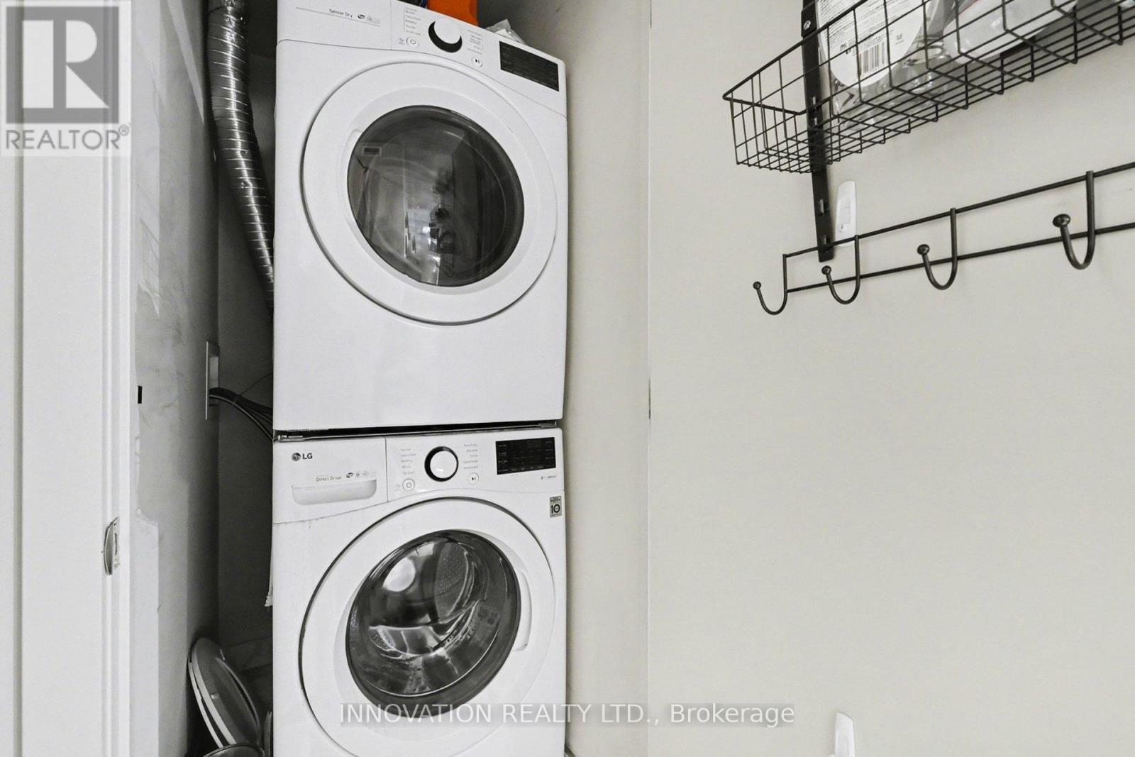 Two washing machines are stacked on top of each other in a small space.