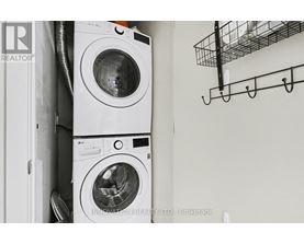 Two washing machines are stacked on top of each other in a small space.