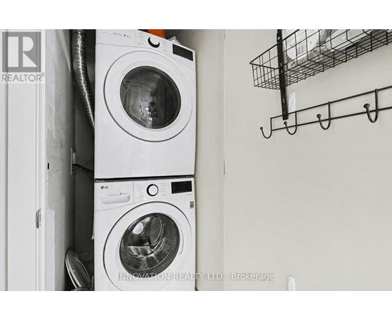 Two washing machines are stacked on top of each other in a small space.