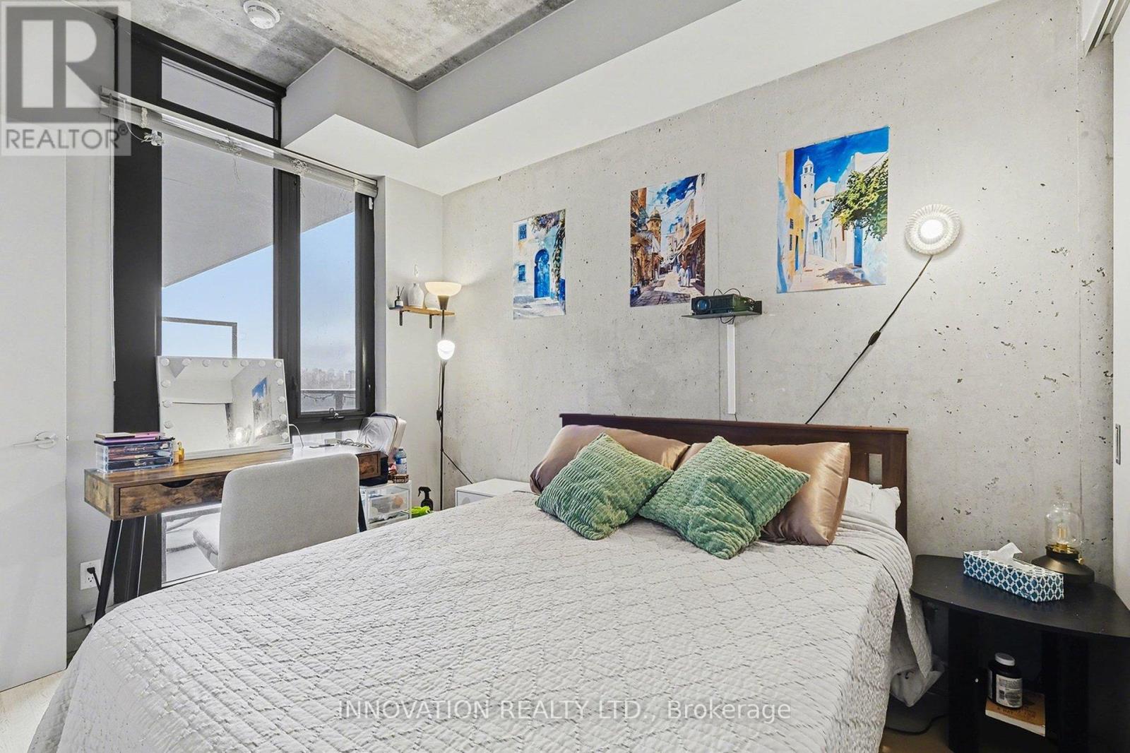 A bedroom with a large bed and a desk with a lamp.