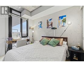 A bedroom with a large bed and a desk with a lamp.