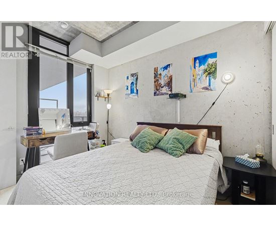 A bedroom with a large bed and a desk with a lamp.