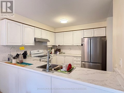 A kitchen with white cabinets and a marble countertop.