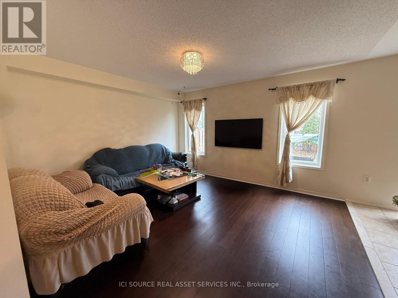 A living room with a couch, a coffee table, and a flat screen TV.