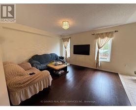 A living room with a couch, a coffee table, and a flat screen TV.
