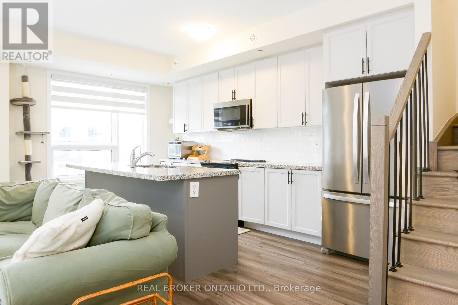 A kitchen with a green couch and a stainless steel refrigerator.
