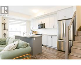 A kitchen with a green couch and a stainless steel refrigerator.