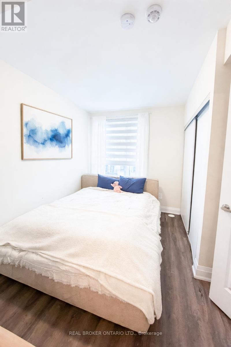 A bedroom with a bed, a painting, and a door.